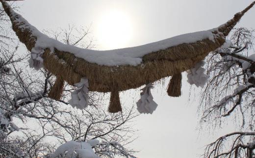 「赤湯冬点描3」烏帽子山八幡宮の参道に立つ継ぎ目なしの石の大鳥居は日本一といわれています その大鳥居に下がる注連縄も大きく 春祭りには恒例の注連縄飾りが行われ 新聞やテレビで毎年のように報道される伝統の行事です 雪を頭に乗せ重そうにさがっています/