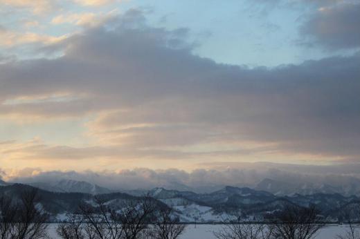 早春の山並み 朝から柔らかな日差しが雪を照らしてくれています 東の空に浮かぶ雲が少し赤みを帯び遠くの山並みを照らしています真っ白だった山が雪と木々がまだらな山を色づけて春らしい感じの山になってきました 少〜し春の兆しが感じられる朝のひと時です/