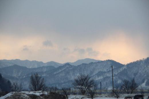 早春の山並みが朝焼けの染まっています どことなく春を感じさせてくれる風景です 犬を連れて散歩している様子もどこか春の雰囲気を漂わせてくれています 今日も寒さは和らいだ天気のようです/