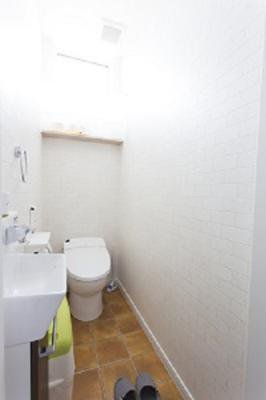 テラコッタタイル調の床とレンガクロスのトイレ：画像